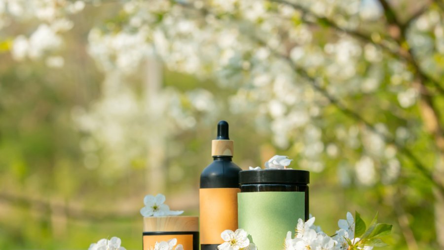 Cosmetic jar on wooden table in blooming tree spring garden