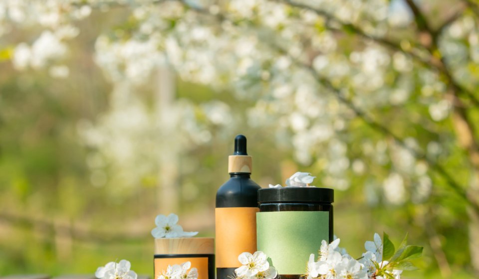 Cosmetic jar on wooden table in blooming tree spring garden