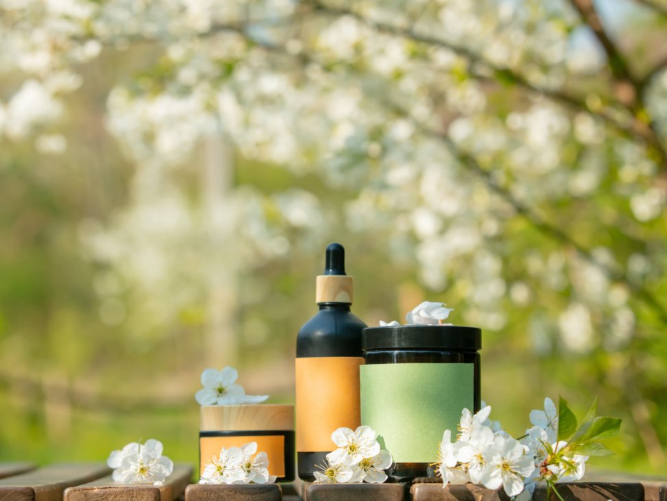 Cosmetic jar on wooden table in blooming tree spring garden