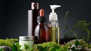 Group of skin care products with moss and leaves on black background
